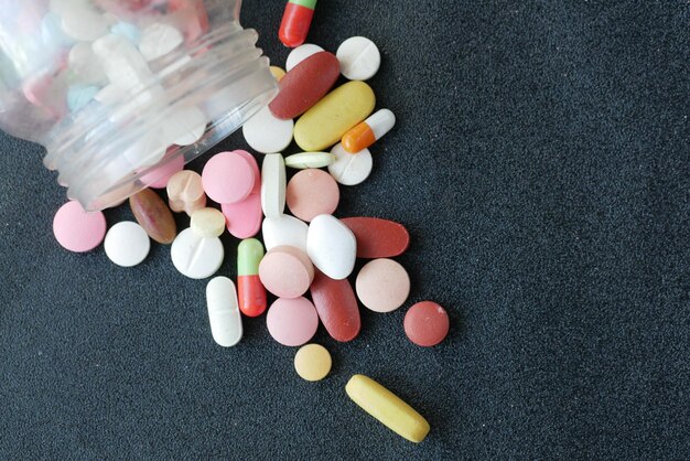 Primo piano di molte pillole e capsule colorate su sfondo nero
