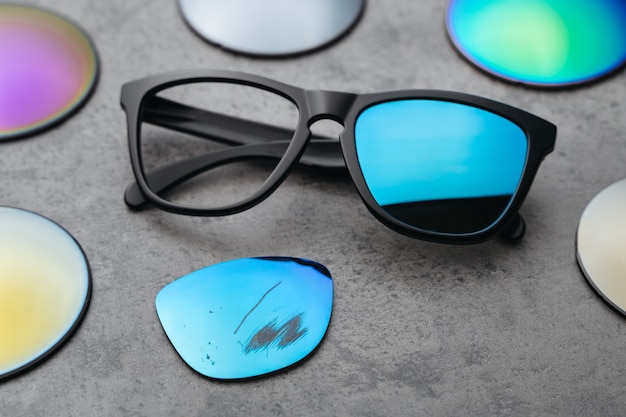 Primo piano di occhiali rotti con lenti colorate danneggiate circondate da lenti diverse