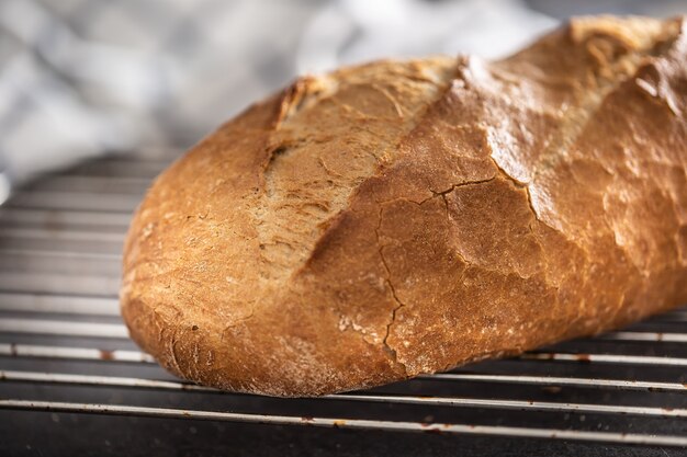 Primo piano di pane casalingo fumante caldo su una scrivania da cucina scura.