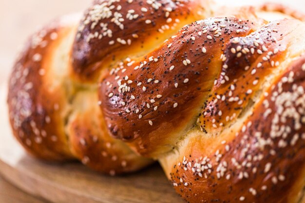 Primo piano di pane challah intrecciato con sesamo e semi di papavero.