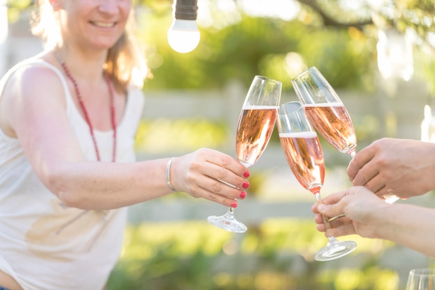 Primo piano di persone che tostano con champagne all'aperto