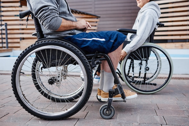 Primo piano di persone con disabilità sedute su sedie a rotelle e parlando tra loro trascorrono il tempo...