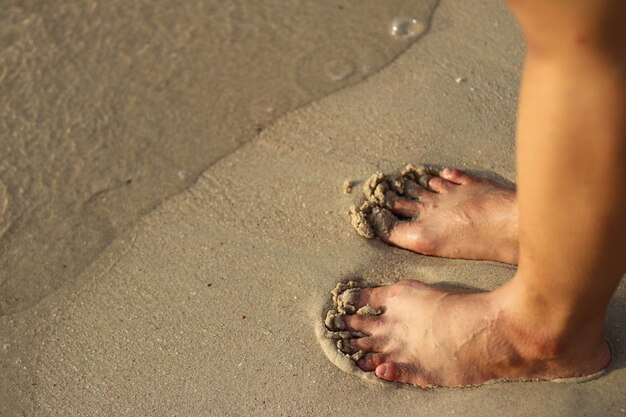 primo piano di piedi in piedi sulla spiaggia di sabbia