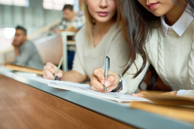 Primo piano di ragazze che prendono appunti in classe