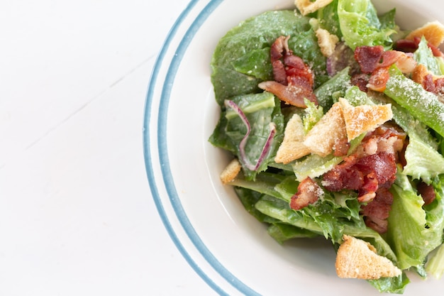 Primo piano di sana insalata Caesar con crostini di pane e prosciutto affettato