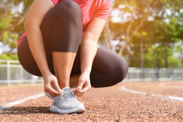 Primo piano di scarpe da corsa di allacciatura della giovane donna per fare jogging all&#39;aperto. Concetto di stile di vita sano.