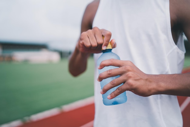 Primo piano di sport a mano uomo tenere bottiglia d'acqua corridore stanco e assetato dopo aver eseguito allenamento acqua potabile Concetto di uomo sportivo