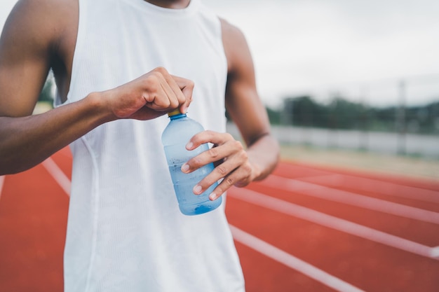 Primo piano di sport a mano uomo tenere bottiglia d'acqua corridore stanco e assetato dopo aver eseguito allenamento acqua potabile Concetto di uomo sportivo