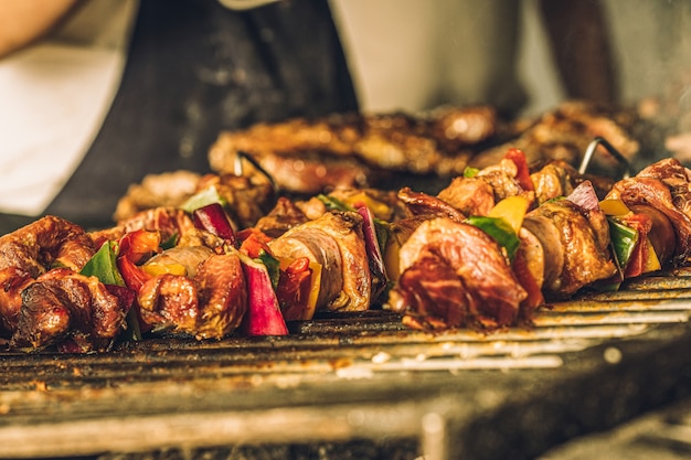 Primo piano di squisiti spiedini di carne con verdure che cucinano alla griglia.