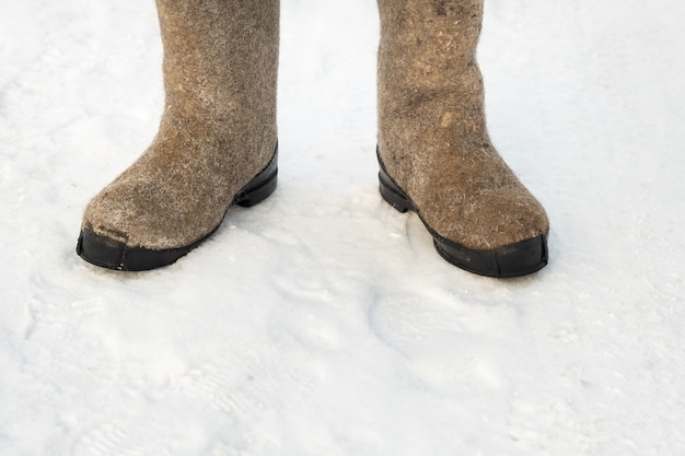 Primo piano di stivali di feltro in piedi nella neve.