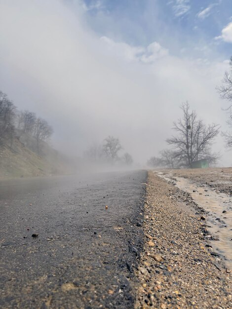 Primo piano di strada bagnata nella nebbia in terreno montuoso Strada asfaltata dopo la pioggia in caso di nebbia e tempo nuvoloso