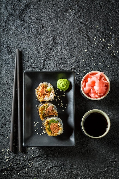 Primo piano di sushi con salmone e avocado su roccia nera