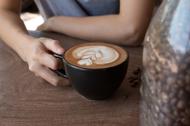 Primo piano di tazza di caffè caldo arte latte sul tavolo di legno