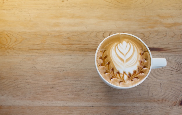 Primo piano di tazza di caffè caldo arte latte sul tavolo di legno.