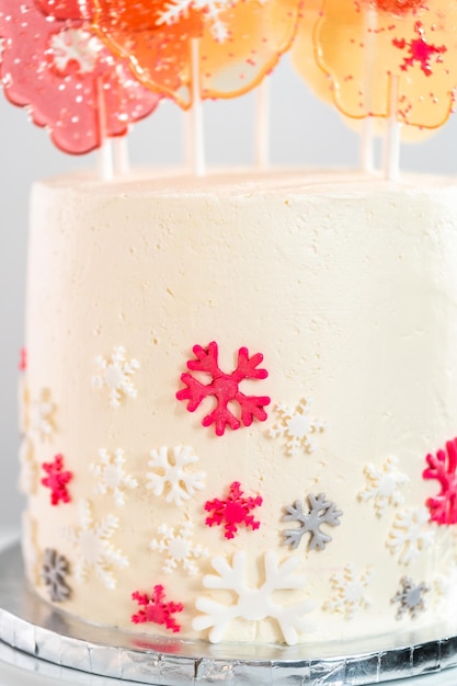 Primo piano di torta rotonda con glassa di crema al burro italiana decorata con fiocchi di neve fondente.