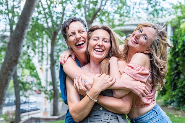 Primo piano di tre amiche mature allegre che si abbracciano insieme. Amici di mezza età che condividono il tempo insieme e si divertono.