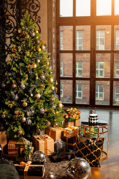 Primo piano di un albero di Natale decorato con palline d'oro. Sotto l'albero di Natale un gran numero di regali di Natale. Concetto di vacanze di Natale