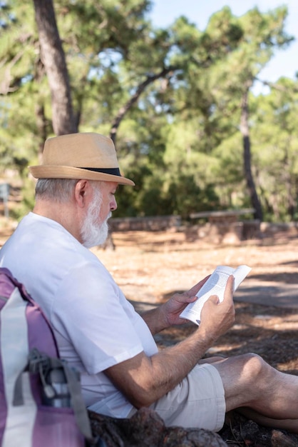 Primo piano di un anziano pensionato che legge un libro sotto un albero