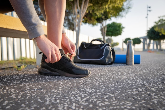 Primo piano di un atleta che si allaccia le scarpe con l'attrezzatura per l'allenamento accanto a lui