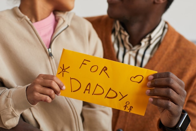 Primo piano di un bambino afroamericano che fa un regalo fatto a mano a papà il giorno del papà, copia spazio