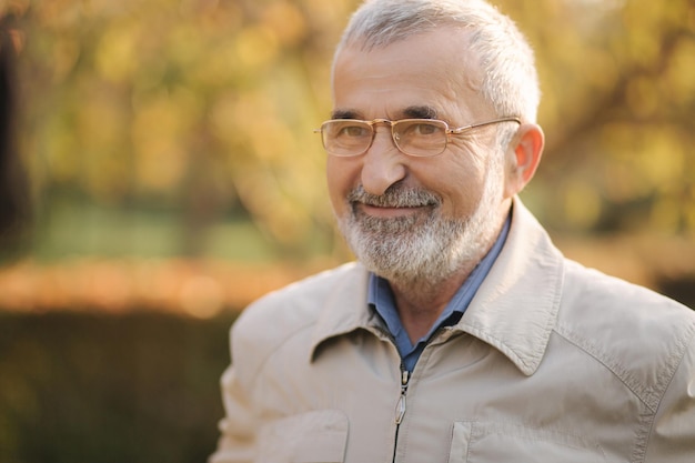 Primo piano di un bell'uomo anziano con bearder indossato gli occhiali Vecchio dai capelli grigi nel parco