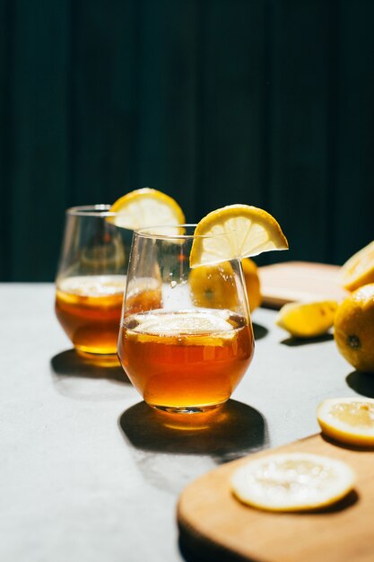 Primo piano di un bicchiere con un cocktail alcolico in un bicchiere con il limone su un grigio