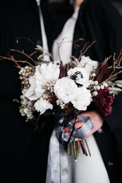 Primo piano di un bouquet bianco con nastri di seta nelle mani della sposa