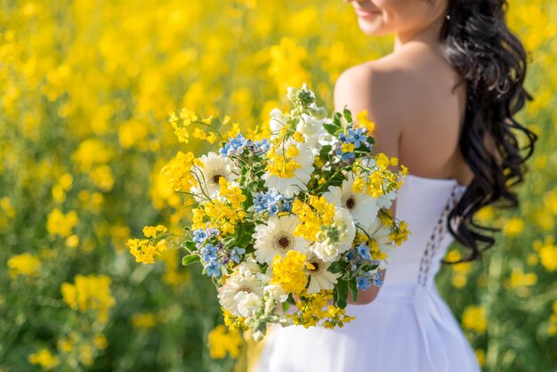 Primo piano di un bouquet da sposa con fiori gialli bianchi e blu nelle mani della sposa Messa a fuoco selettiva