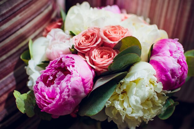 Primo piano di un bouquet da sposa in sordina con fiori rosa e viola.