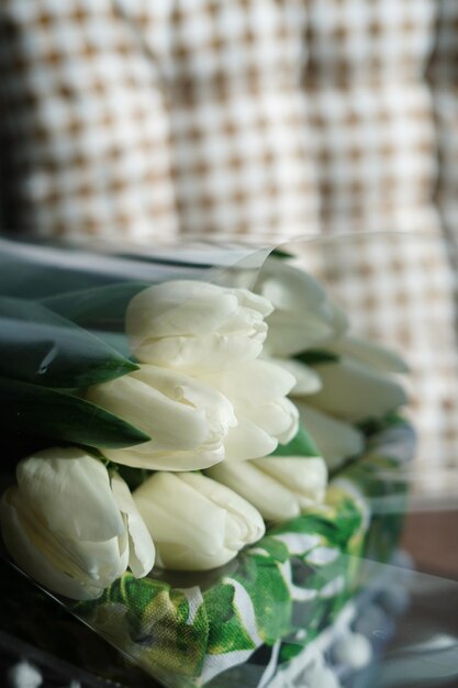 Primo piano di un bouquet di tulipani bianchi. I tulipani bianchi si trovano in un cesto di vimini bianco decorativo