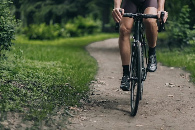 Primo piano di un ciclista con gambe forti che cavalca al parco verde