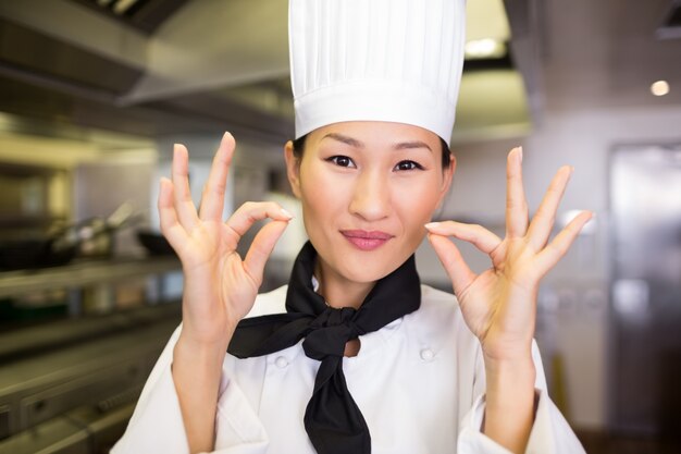 Primo piano di un cuoco femminile sorridente che gesturing segno giusto