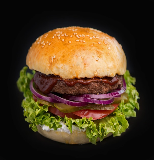 Primo piano di un delizioso hamburger fatto in casa fresco con lattuga formaggio cipolla e pomodoro su una tavola di legno rustica su uno sfondo scuro