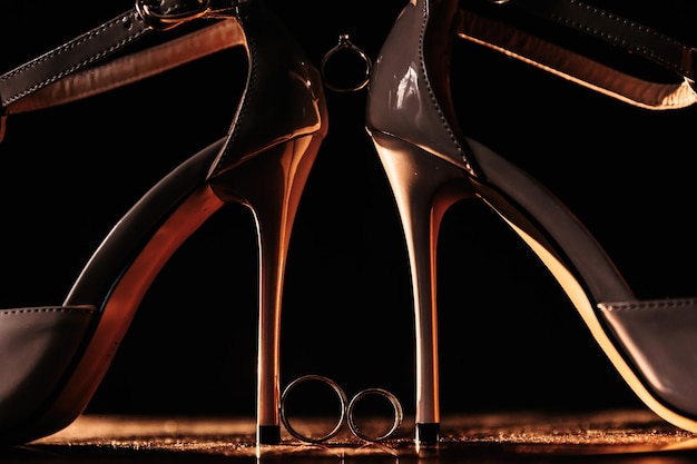 Primo piano di un elegante classico moda scintillante scarpe da sposa tacco alto con un anello di fidanzamento in oro bianco con diamanti posti tra i talloni