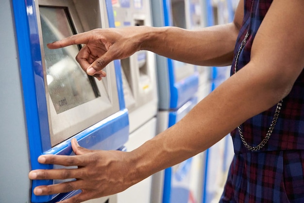 Primo piano di un elegante uomo afroamericano che utilizza il terminale per l'acquisto di biglietti della metropolitana