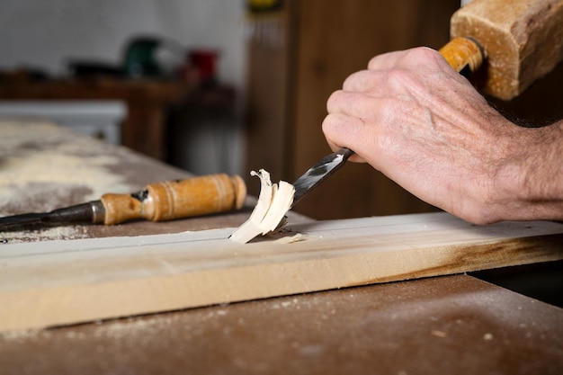 Primo piano di un falegname che intaglia il legno con scalpello Fotografia di alta qualità