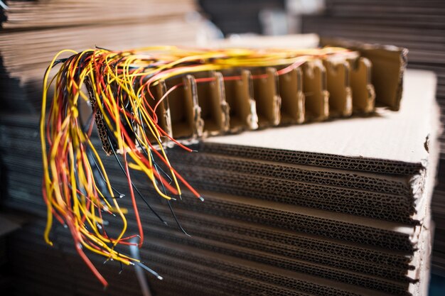 Primo piano di un fascio di fili sottili tagliati con collegamenti colorati che sporgono da essi contro un pannello elettronico sfocato. Il concetto di elettrodomestici in produzione e in fabbrica