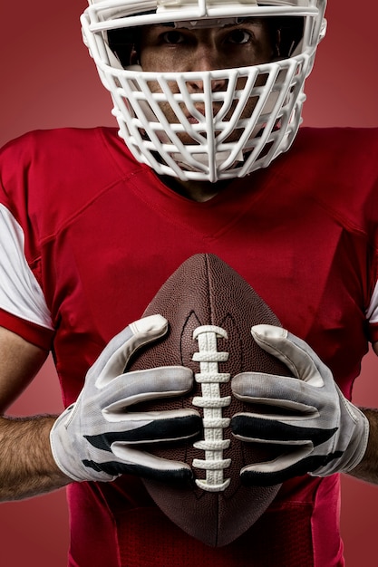 Primo piano di un giocatore di football con una divisa rossa su una parete rossa