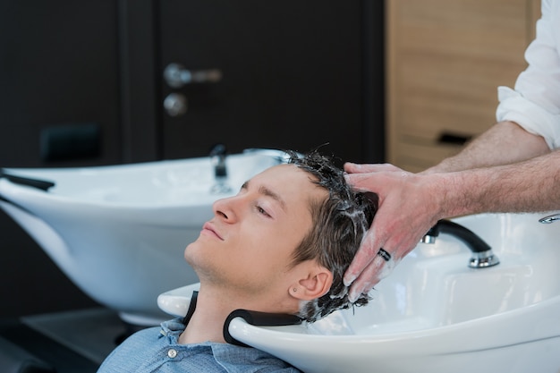 Primo piano di un giovane che fa lavare i capelli nel salone di parrucchiere