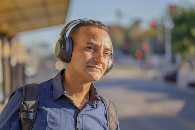 Primo piano di un giovane latino con le cuffie alla fermata dell'autobus