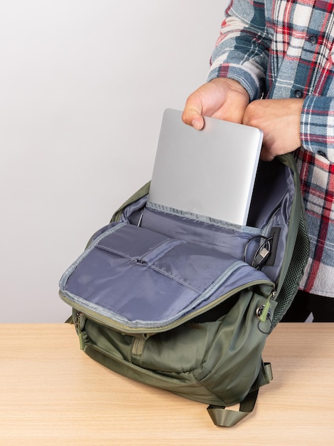 Primo piano di un giovane studente maschio che tira fuori un computer portatile da uno zaino