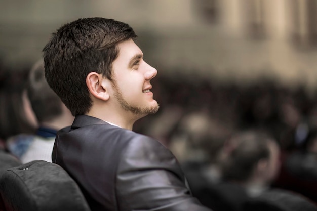 Primo piano di un giovane uomo d'affari di successo in una conferenza d'affari seduto nella sala conferenze