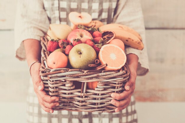 Primo piano di un gustoso secchio di frutta fresca tenuto da mani di donna e copia dello sfondo dello spazio - cibo colorato di stagione per la dieta concetto di stile di vita sano
