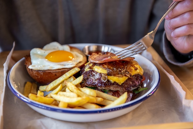 Primo piano di un hamburger di due metà in un piatto con patatine fritte.