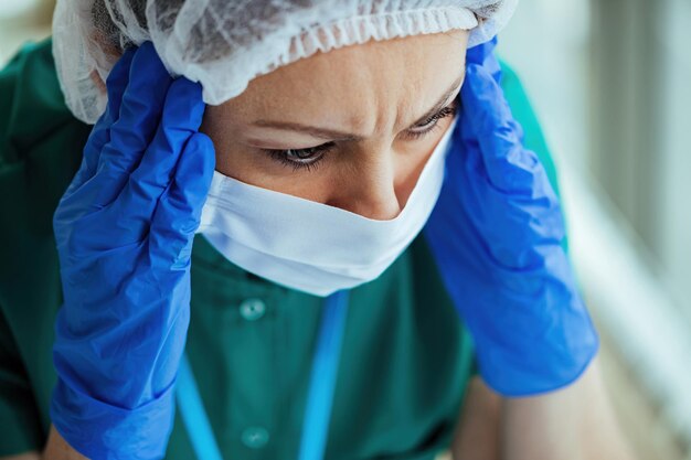 Primo piano di un'infermiera preoccupata che soffre di mal di testa mentre lavora in clinica medica
