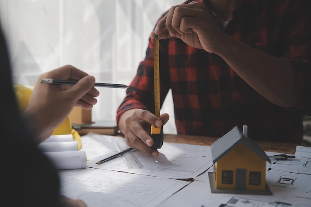 Primo piano di un ingegnere civile maschio asiatico che lavora al progetto architettonico del progetto in cantiere alla scrivania in ufficio