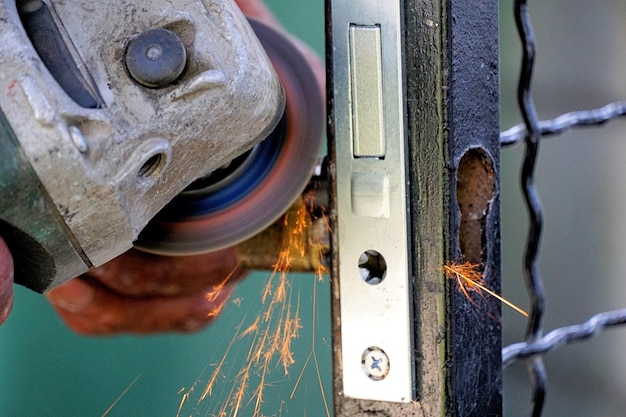 Primo piano di un lavoratore che taglia metallo con una smerigliatrice Scintille durante la macinazione del ferro