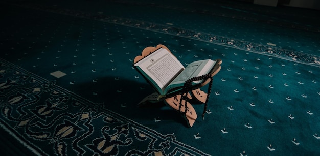Primo piano di un libro sacro aperto del Corano messo su un piedistallo di legno su un tappeto
