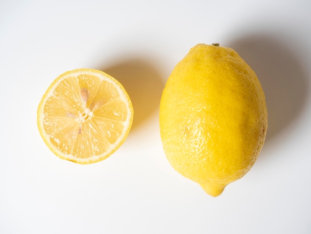 Primo piano di un limone tagliato e intero sdraiato su uno sfondo bianco frutta isolata Frutta gialla acida piena di vitamine Vista dall'alto laici piatta