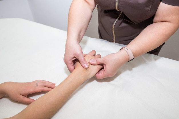 Primo piano di un massaggiatore che fa un massaggio alle mani a una ragazza